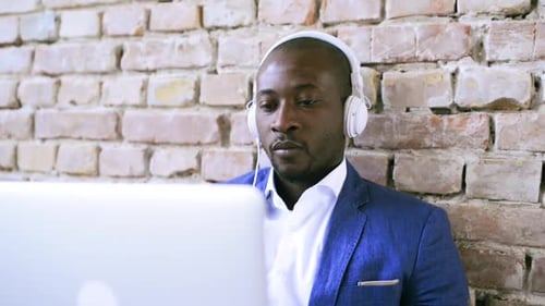 Man with Headphones Working on Laptop in Office