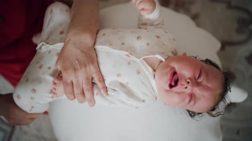 Crying Baby on Bed, being held by an adult