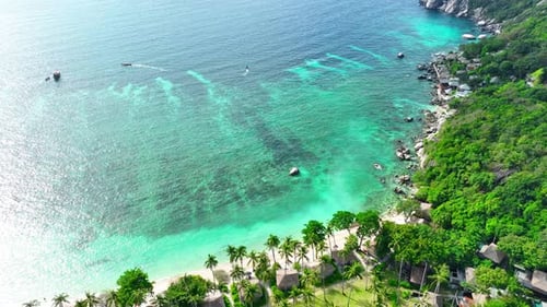 A tropical island with resorts surrounded by clear waters. Drone view.