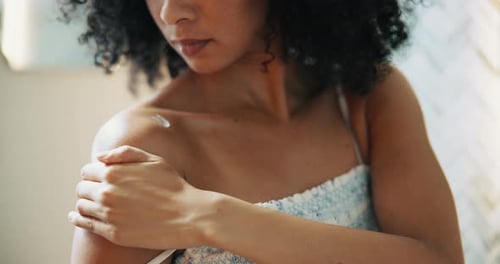 Woman Massaging Lotion Into Her Shoulder At Home
