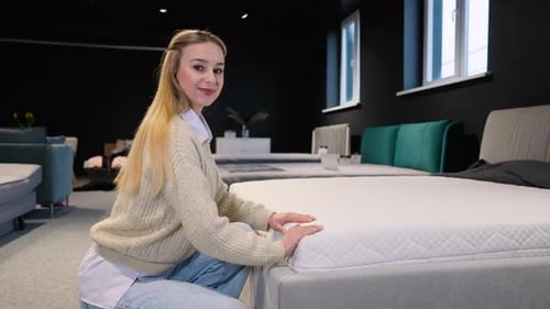 Young Woman Choosing Orthopedic Mattress in Furniture Store