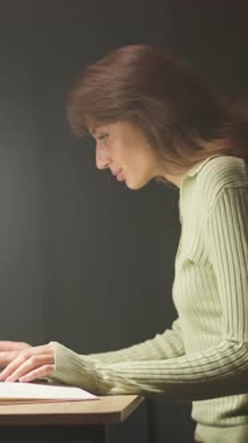 Woman works at desk in front of laptop