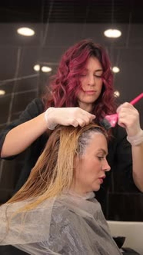 Un coiffeur expérimenté applique soigneusement un colorant de couleur vive sur le coiffeur du client