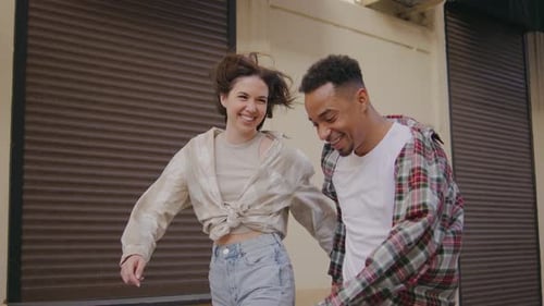 Multiethnic Couple in Love A Couple Walk and Jump Holding Hands on the Street Woman and Man are in a