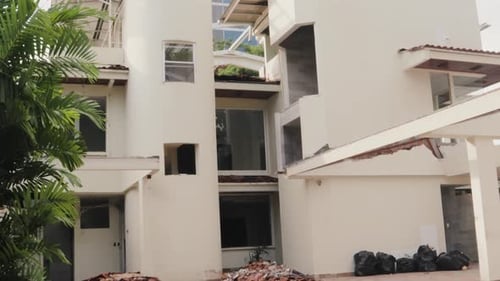 Tilt down shot of a white residential building in a broken condition after earthquake.