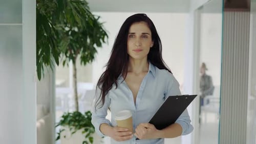 Woman Walking in Office with Coffee and Clipboard