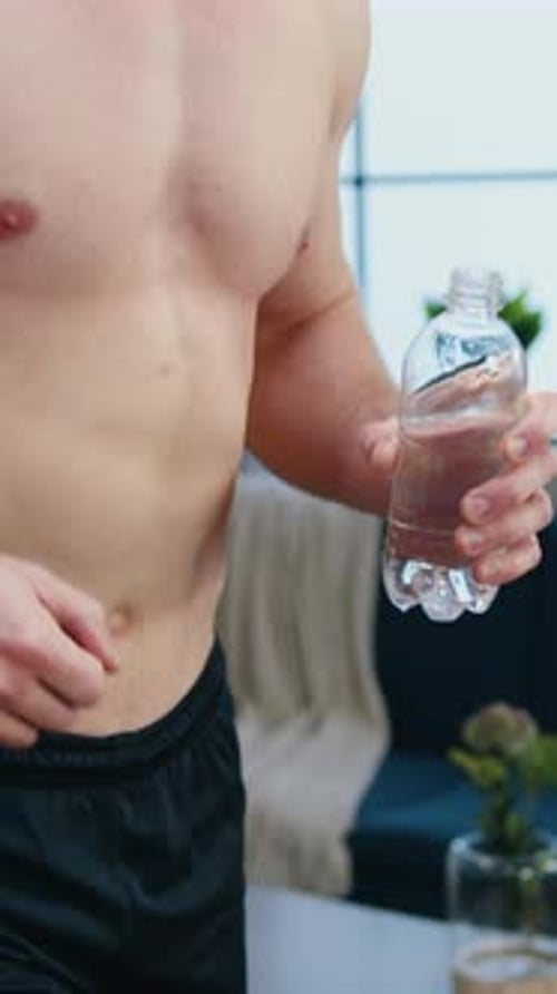 Athletic Man Holding Bottle of Water Indoors
