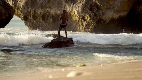 Athletic Man Training on Rock Near Beach