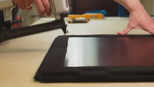 Employee Fixes Fabric Covering on Furniture Details in Shop