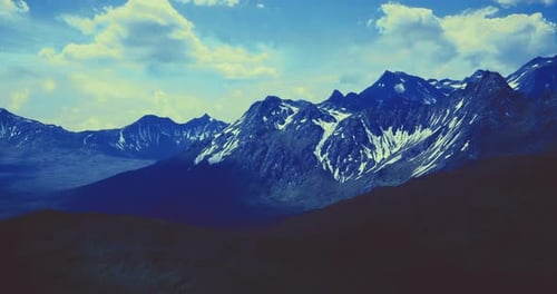 Majestic Mountain Range Under a Dramatic Sky with Clouds and Sunlight