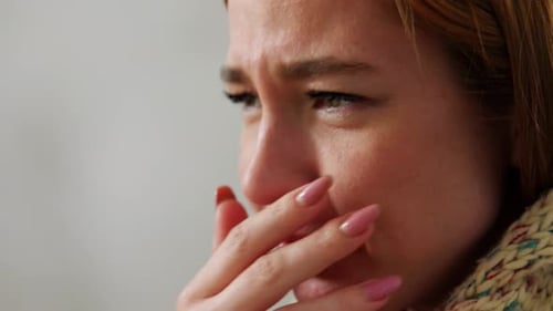 Close-up of a woman sneezing and blowing nose