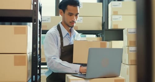 Asian business partner man use laptop computer check inventory online stock data program.