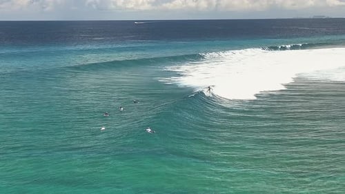 Aerial view of surfer riding a wave in Thulusdhoo, Maldives.