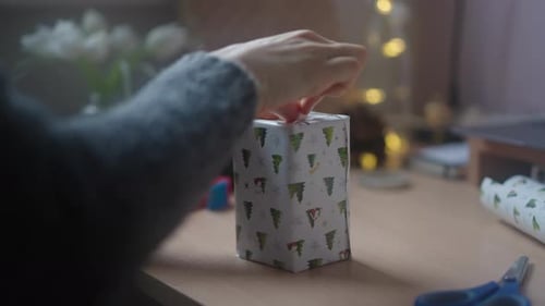 Close up of party host, wrapping and arranging gift boxes with decorative paper.