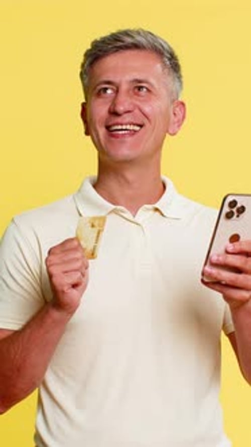 Mann mit Smartphone und Kreditkarte konzentriert sich, während er Zahlungsdetails für den Online-Kauf eingibt