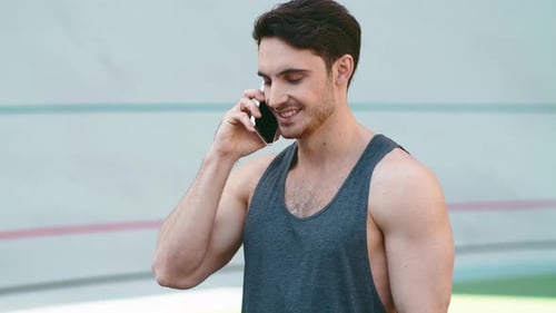 Sporty man talking phone on running track at stadium after outdoor workout