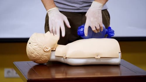 Instructor near mannequin in medical center. Trainer demonstrating cpr procedure on a medical doll.