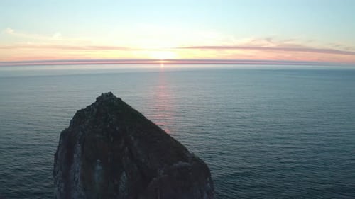 sunset at the ocean. Beach overlooking a stone. flying over a stone during sunset with horizon