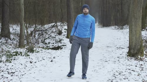 Young Man Stretching Legs Before Jogging in Winter Forest Active
