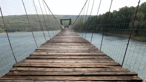 Niedriger Winkel der Hängebrücke mit Holzdeck über den Gebirgsfluss.