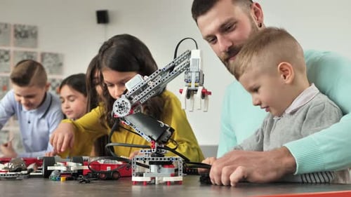 Young Father and Son Assemble a Construction Kit at a Robotics School