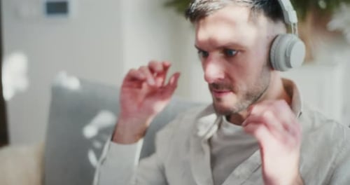 Man Using Laptop and Headphones on Sofa