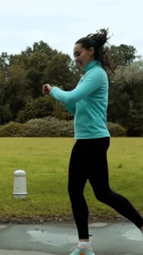 Woman Doing Jumping Jacks Outdoors in Park