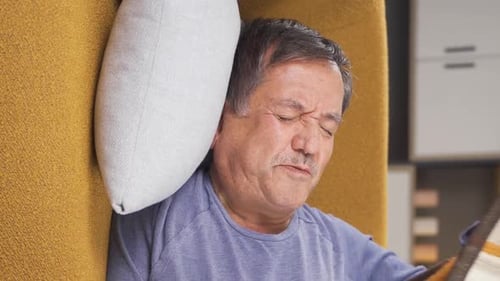 Man Lying on Couch in Discomfort