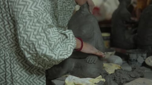 Person sculpting a clay figure in an art studio, close-up