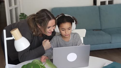 Woman Helping Girl with Laptop at Home