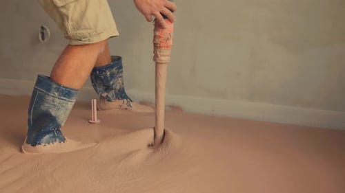 Worker leveling wet concrete on a floor using a trowel