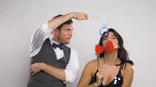 Happy young couple posing with party props in fun celebration indoors