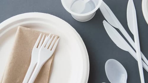 Concepto de alimentación, reciclaje y ecología: platos de plástico desechables sobre fondo gris