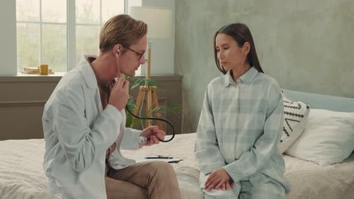 Doctor Examining Young Woman with Stethoscope in Home