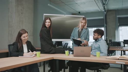 Team collaborates in office with documents and a laptop in slow motion during a business meeting