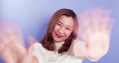 Portrait of Asian happy woman is waving to the camera and doing hello gestures while standing isolat