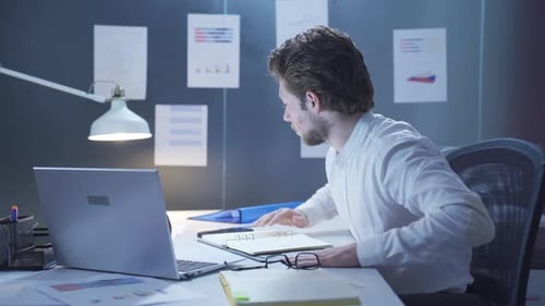 Young Adult Working on Laptop in Office at Night