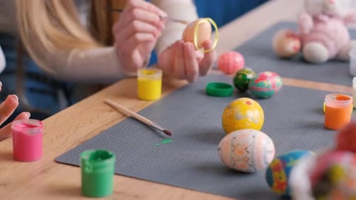 Woman Decorating Easter Eggs at Table with Water Using Natural Food Dyes