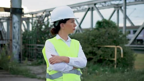 Woman Civil Engineer with Arms Crossed by Bridge
