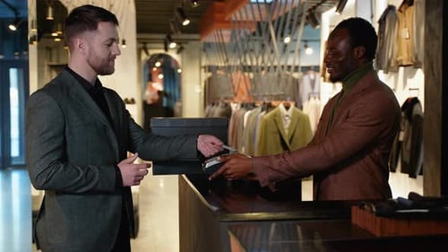 A Man In Clothing Store Making Contactless Payment With Credit Card