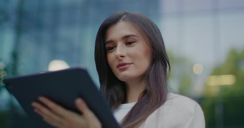 Woman Uses Tablet Outside Modern Building