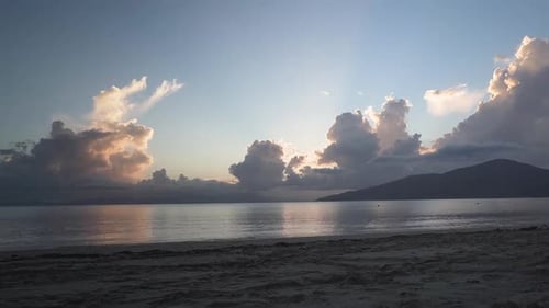 Zeitraffer am Strand bei Sonnenuntergang mit Sonnenstrahlen durch die Wolken