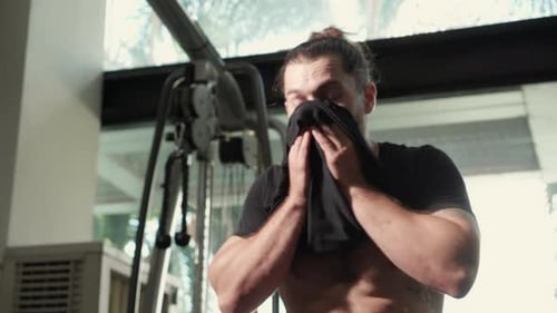 Young caucasian man tired after effort exercise in fitness gym, man sweat sitting expression.