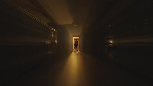 Dark Hallway with Man Walking Toward Camera