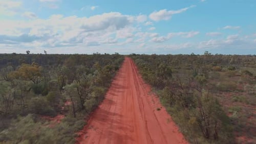 Drone shot, A deserted desert track with bright red soil in the Australian outback.