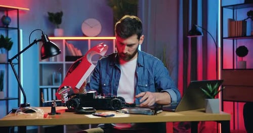 Man Building Red Toy Car at Desk