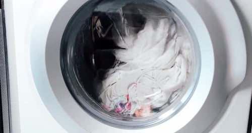 Water Filling Modern Washing Machine with Laundry Close Up