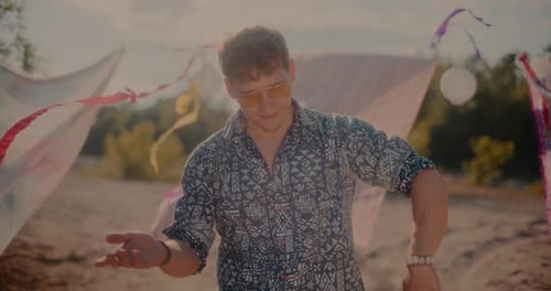Hombre atractivo y sonriente que disfruta de la música mientras disfruta en la playa