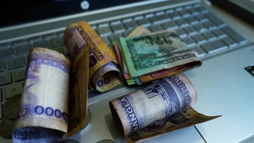 Close Up of Currency and Coins on Laptop