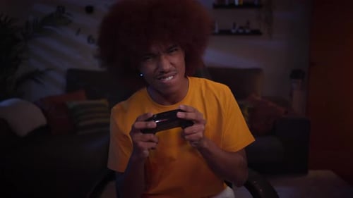 Focused Young Adult Playing Video Games at Night